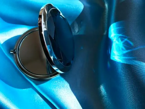 A small mirror on a blue fabric. Stock Photos