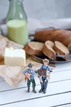 Small models farmers with sliced bread with a milk and butter on a on natural Stock Photos