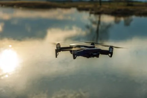 Small modern drone hovering taking picture of sunset. Stock Photos