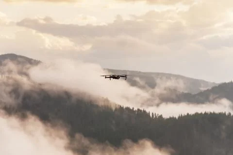 Small modern drone hovering taking picture of sunrise in mountain. Foto stock