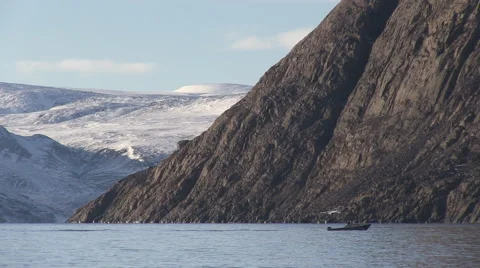 Small motor boat heads down the Arctic sea in front of snowy mountains. Видео 68981687