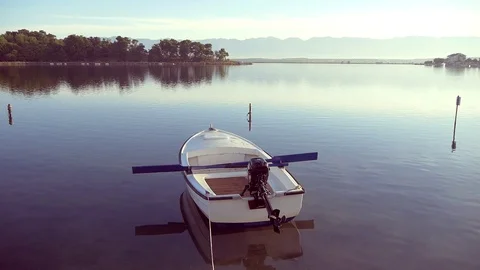 Small Motor Boat With Oars On Calm Lake In The Morning Stock Footage 98673249
