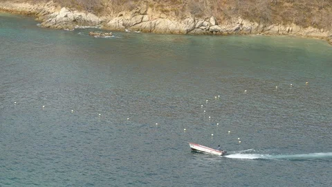 Small motor boat pulling a towable banana boat at Huatulco Mexico Stock-Footage 107026595