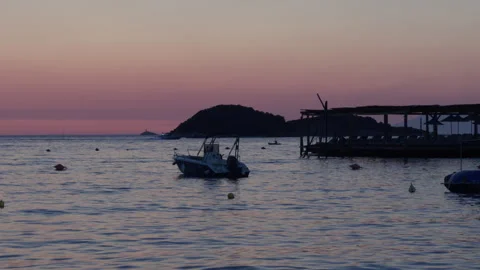 A small motorboat floating on calm waters at sunset along the Albanian Rivier Stock Footage 338850195