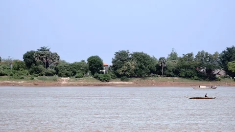 Small motorized dugout canoe pulling behind an heap of bamboo poles down a river Video stock 113304132