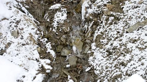 Small mountain brook flowing on stony snow covered soil in winter Stock Footage 50085602