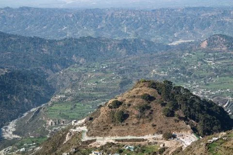 A small mountain in one third frame with wide hill ranges in the background. Stock Photos