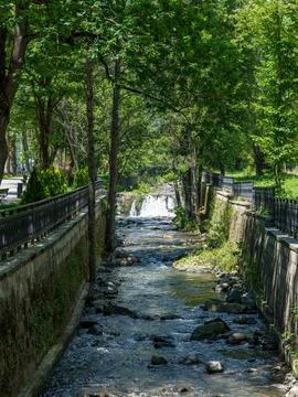 Small mountain river flowing through green park embankment in resort town Фото