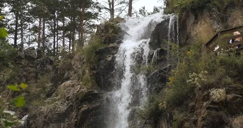 Small mountain river flows, it cascades from cliff, waterfall cuts stone Stock Footage 118296569
