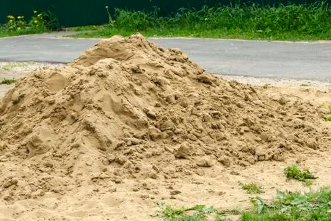The small mountain of river sand is poured out on the road for construction Stock Photos