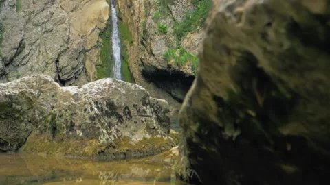 Small mountain waterfall in slow motion. Cinematic camera movement between rocks Stock Footage 154222303