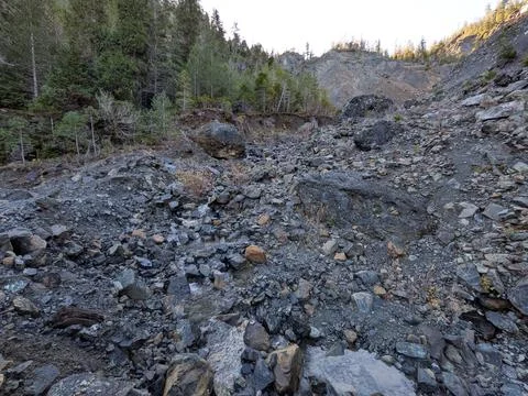 A small mountain waterfall stream flows downhill across rugged rocks Stock Photos