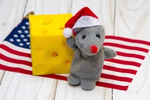 A small mouse with a piece of cheese on the background of the American flag. Fotos de archivo