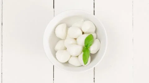 Small mozzarella balls in a plate with basil leaves. Healthy food. Stock Photos