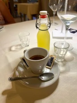 A small mug of espresso on the table next to a bottle of homemade lemoncello Stock Photos
