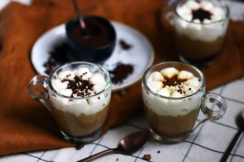 Small mugs with a three-layer coffee-caramel dessert. Delicious pudding in gl Stock Photos