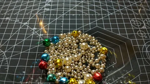 Small multi-colored beads are poured into a glass bowl Stock Footage 282129854