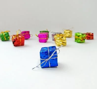 Small multi-colored boxes with gifts are scattered on a white background Stock Photos