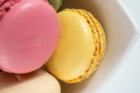 Small multi-colored macaroons in a white plate on a white background Stock Photos