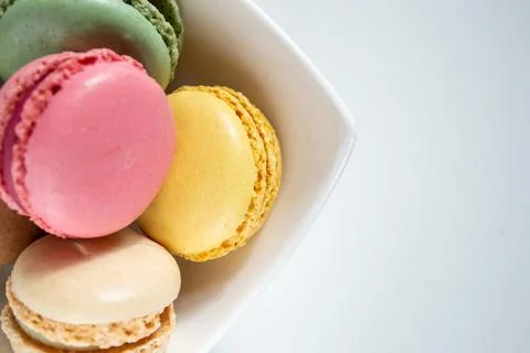 Small multi-colored macaroons in a white plate on a white background Stock Photos