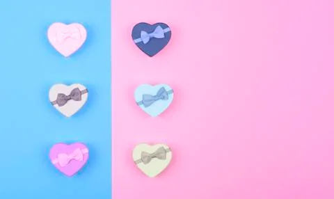 Small multicolored gift boxes hearts on blue and pink background, top view, c Stock Photos