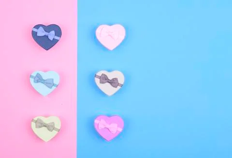Small multicolored gift boxes hearts on blue and pink background, top view, c Stock Photos