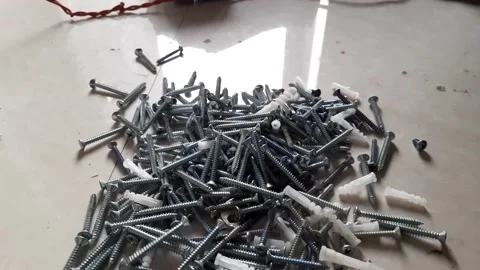 Small nails, nuts, and bolts scattered on top of the Whiteboard Stock Footage 151661078
