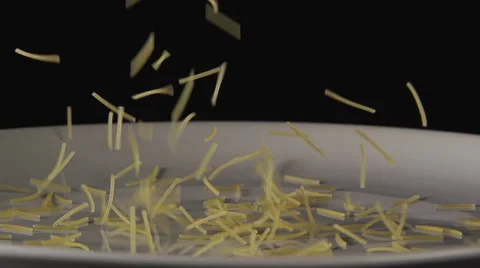 Small noodles fall on a white dish and jump on it Stock Footage 62425764