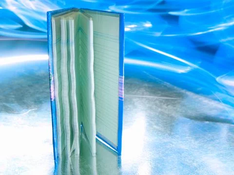Small note book diary presented around blueish light effect with reflection. Stock Photos