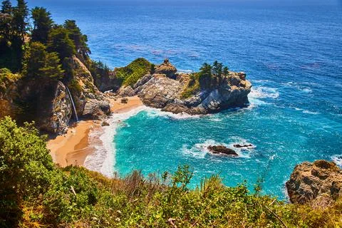 Small ocean cove surrounded by cliffs, waterfall, and sandy beaches Foto stock