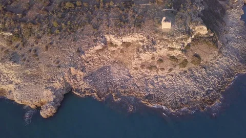 Small ocean waves below rocky cliff aerial view from 4k drone on sunset Video stock 84052127