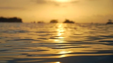 Small ocean waves lit up by a warm sunset Stock Footage 93782647