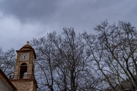 A small old clock tower against a backdrop of autumn trees and a stormy sky. Stock Photos