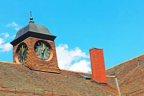 Small old clock tower on a red tiled roof against of the blue sky in Geneva.. Stock Photos