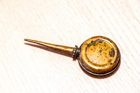 A small, old-fashioned metal object with a pointed end sits on a wooden surfa Stock Photos