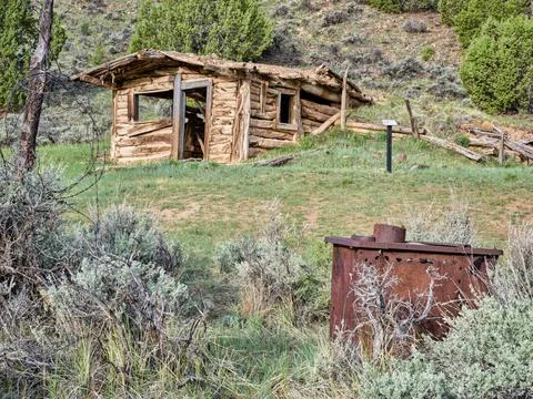 Small, old, log cabin sits on a hillside Stock Photos