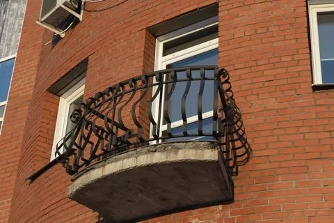 A small open balcony on the facade of a brick building. Stock Photos