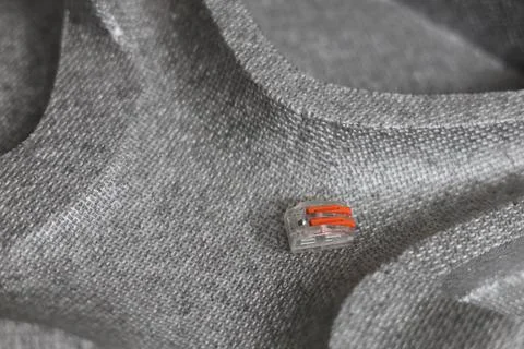 Small orange and clear electrical wire connector on textured surface Foto stock