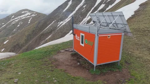 Small orange mountain hut with solar panels Stock Footage 345387820