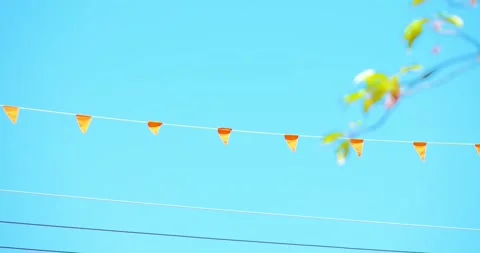 Small orange pennant flags on wire under bright blue sky Stock Footage 333943037