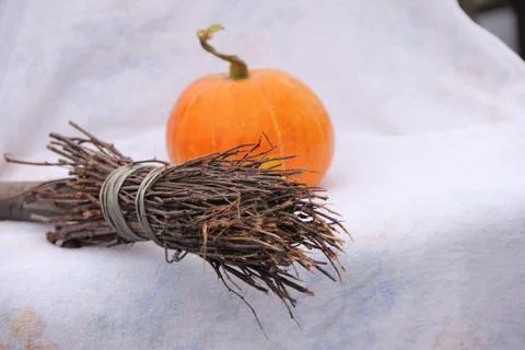 A small orange pumpkin and a broom lie on a white background Stock Photos