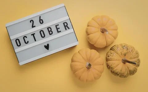 Small orange pumpkins on yellow background with october calendar Stock Photos