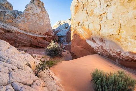 A small orange sand dune between massive sandstone rock formations Stock Photos