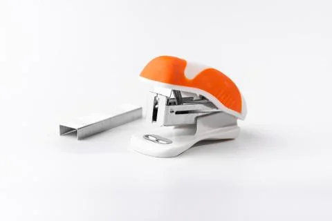 A small orange stapler and staples on a white background. Close-up. Copy spac Stock Photos