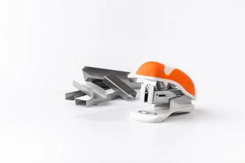 A small orange stapler and staples on a white background. Close-up. Copy spac Stock Photos