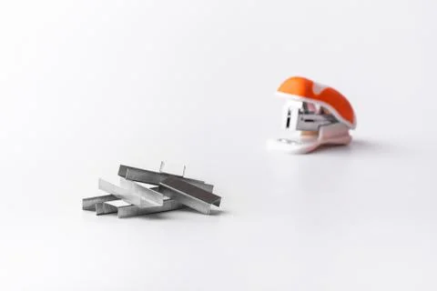 A small orange stapler and staples on a white background. Close-up. Copy spac Stock Photos