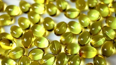 Small oval transparent gel capsules have a yellow oily liquid inside. Dietary su Stock Footage 144952384