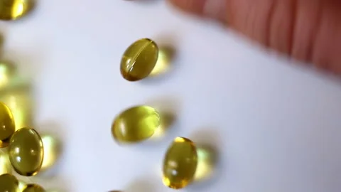 A small oval transparent yellow capsule is raked by hand. Real-time, close-up, m Stock Footage 145106999