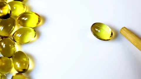 A small oval transparent yellow capsule rotates on a white background. Real-time Stock Footage 145107012