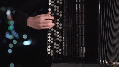 Small pan close up of musician playing accordion on beautiful night city lights Stock Footage 212422699